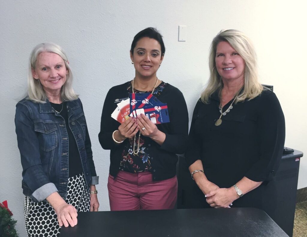 eanie Spies, President, and Cathe Robling, Treasurer, present gas and food gift cards to Arlette Mendoza, NMCRS Director at MCAS Mirmar