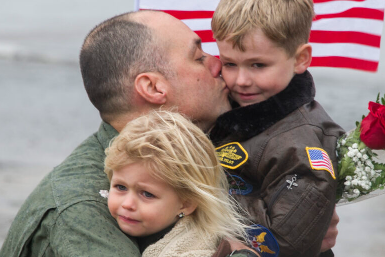 US Navy Aviator hugs his kids during the squadron's homecoming